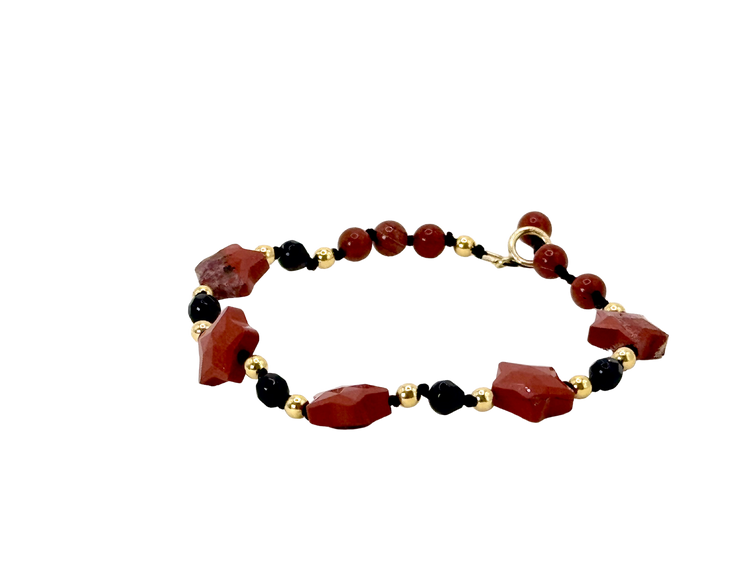 La simplicité fun du lien, la lumière des étoiles.
Bracelet sur cordon - Perles étoile en jaspe rouge - Perles d'onyx noire, jaspe rouge et en or laminé 14 carats.
J'ai noué chaque perle entre elles, comme un acte de solidarité et de compassion.