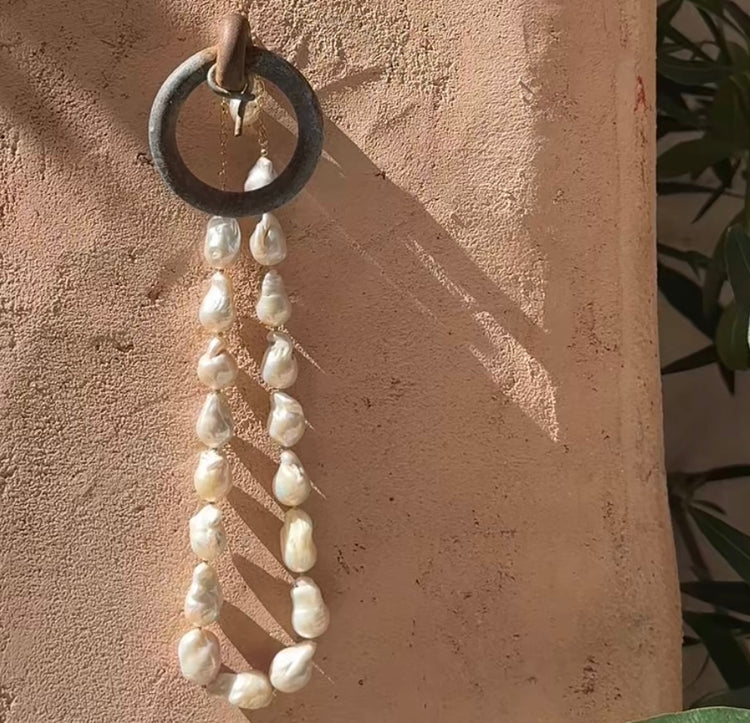 Collier sur chaîne en or laminé - Perles keshi (perles de culture dites "baroques") 1,5cm environ, perles en or laminé 14 carats.
Ce collier met à l’honneur la perle keshi dans toute son authenticité. Chaque perle, naturellement formée, révèle des reflets nacrés et une texture organique qui en font une pièce unique. Assemblées à la main, elles composent un bijou à la fois moderne, raffiné et intemporel.